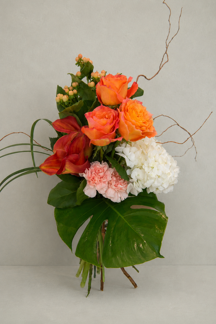 Bouquet of flowers with orange, red, and white flowers on a light gray background